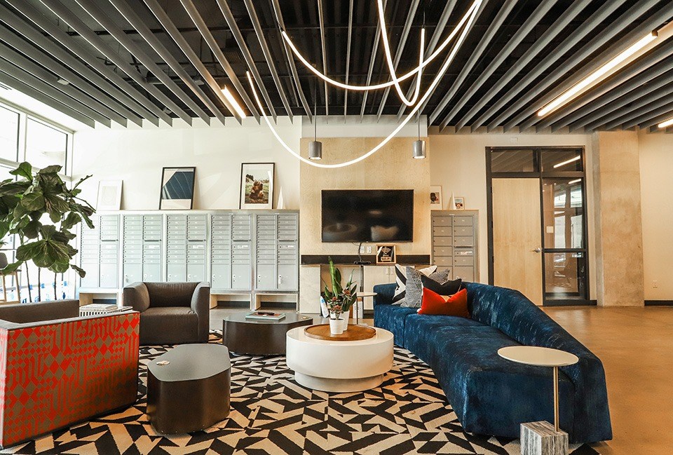 A living room with a blue couch and a black and white patterned rug at RiDE at RiNo Apartments, Denver