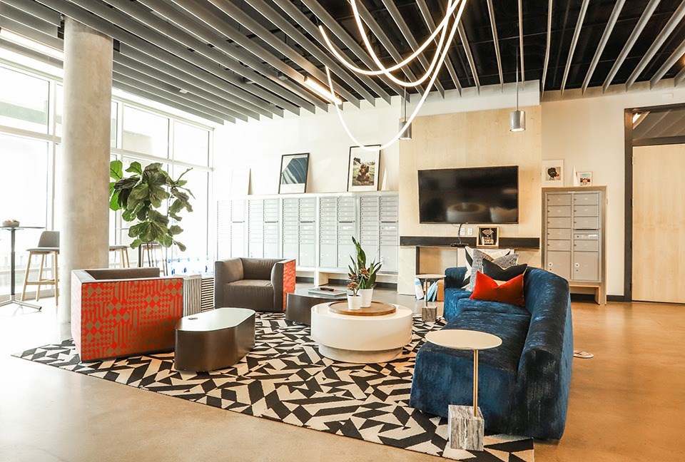 A living room with a blue couch and a black and white rug. at RiDE at RiNo Apartments, Denver, CO
