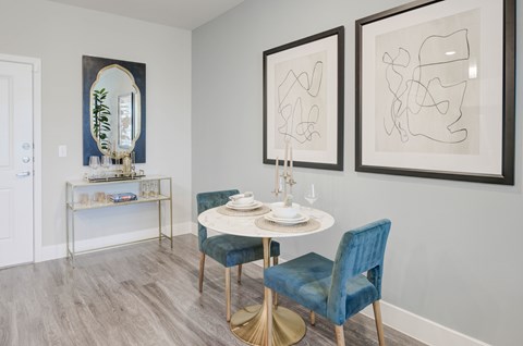 A dining room with a round table and blue chairs.