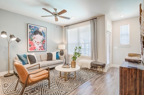 A living room with a patterned rug, a sofa, a chair, a coffee table, and a painting on the wall.
