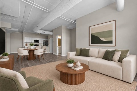 A living room with a white couch, a green armchair, a wooden coffee table, and a painting on the wall.