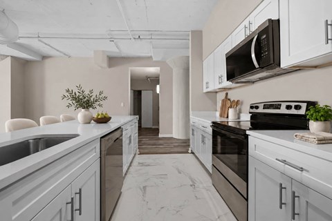 A modern kitchen with white cabinets and a marble countertop.