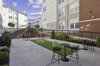 an outdoor patio with tables and chairs in front of apartment buildings at West 130, West Hempstead, NY 11552