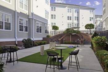 a patio with tables and chairs in front of a building at West 130, New York , 11552