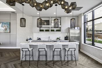 a kitchen with a marble counter top and bar stools at West 130, West Hempstead, New York