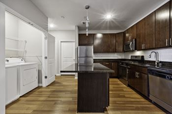 a kitchen with dark wood cabinets and white appliances at West 130, West Hempstead