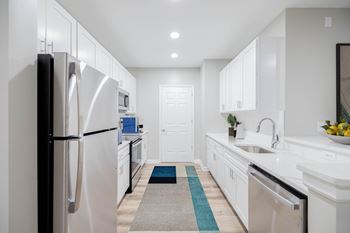 A modern kitchen with white cabinets and a black refrigerator.