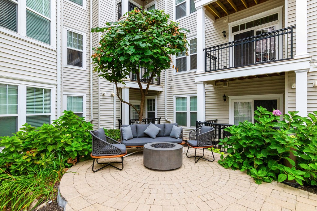 a patio with a firepit and seating area in front of an apartment building at Metro 303, Hempstead, 11550