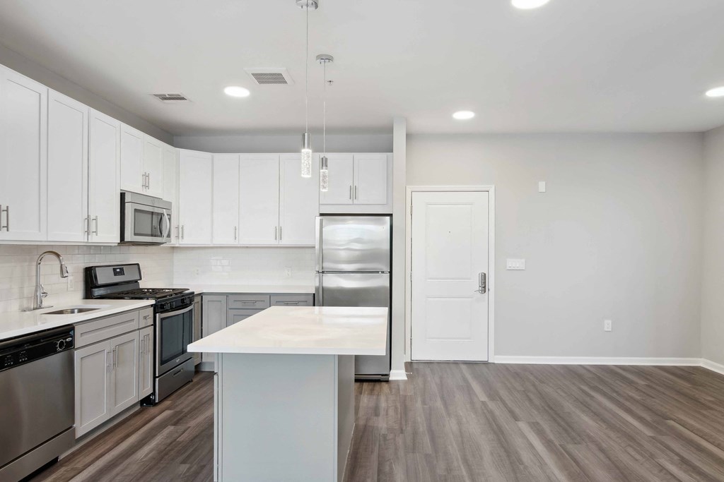 a kitchen with white cabinets and stainless steel appliances at Metro 303, Hempstead New York