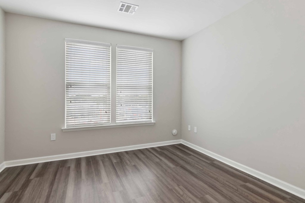 a bedroom with hardwood floors and a large window at Metro 303, Hempstead