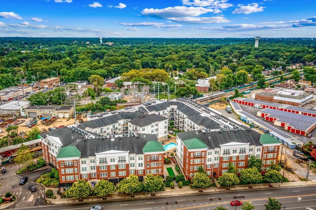 an aerial view of a large building complex with trees in the background and a blue sky with at West 130, West Hempstead, NY