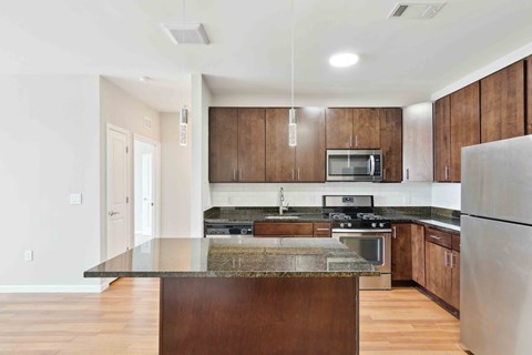 a kitchen with dark wood cabinets and an island with granite countertops a kitchen with dark wood cabinets and an island with granite countertops at West 130, New York