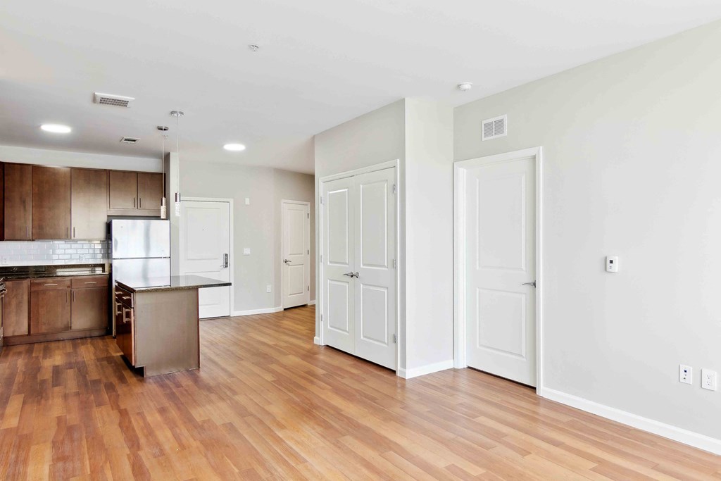 an empty living room with a kitchen in the background at West 130, West Hempstead, NY 11552