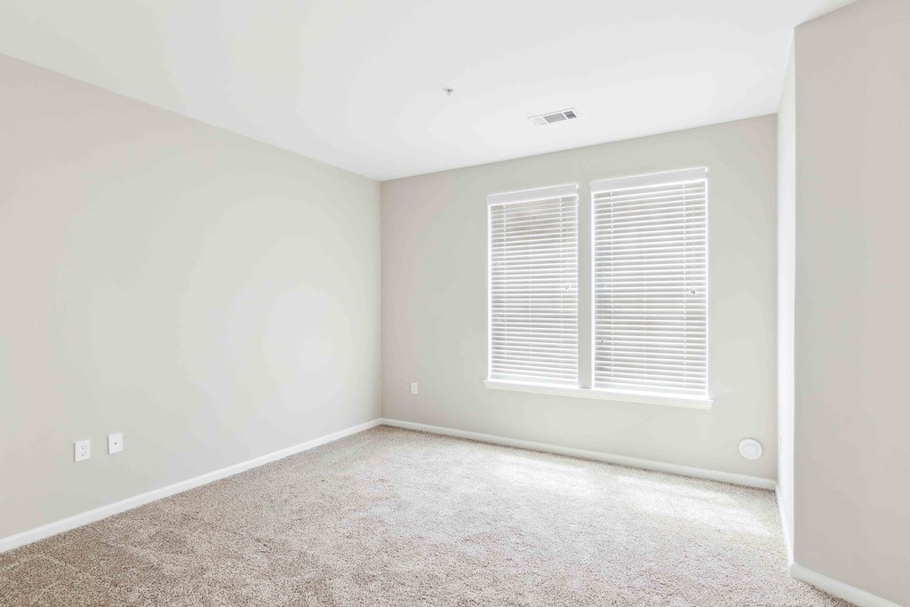a bedroom with white walls and a window with white shutters at West 130, West Hempstead