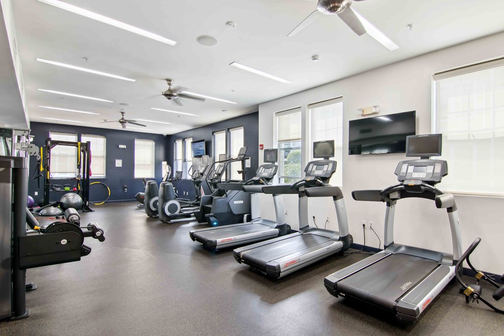 a gym with cardio equipment and a flat screen tv at West 130, West Hempstead New York