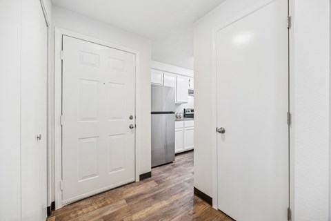 A kitchen with white cabinets and a white door.