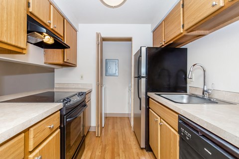 A kitchen with wooden cabinets and a black refrigerator.