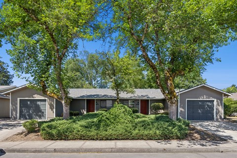 A house with a red door is surrounded by green trees.