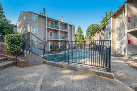A pool surrounded by a black fence in front of a building.