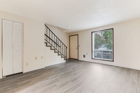 the living room and entryway of an empty house with white walls and wood floors