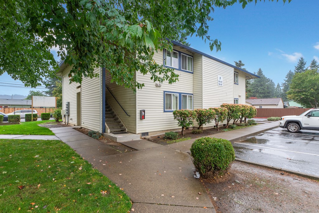 the exterior of a yellow house with a rainy sidewalk