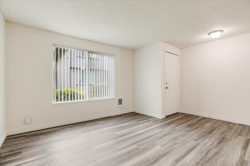 A room with a window and wooden flooring.