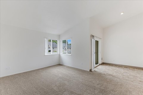 A spacious room with a carpeted floor and a door leading to another room.
