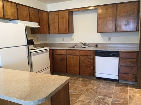A kitchen with brown cabinets and a white dishwasher.