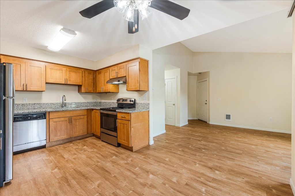 A kitchen with wooden cabinets and a black fan.