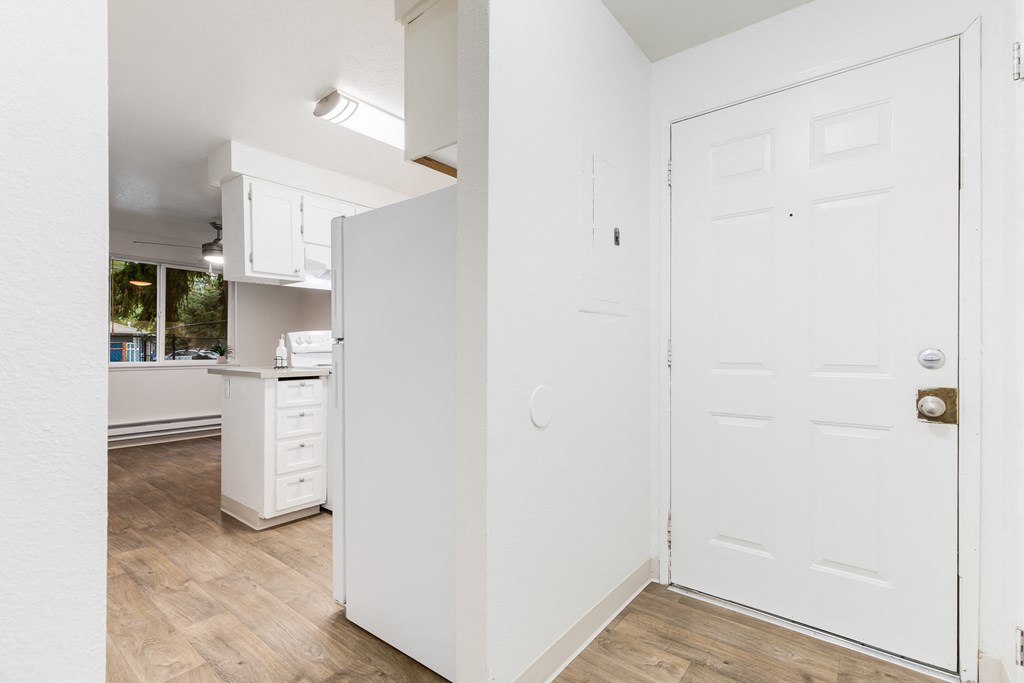 an empty kitchen with white cabinets and a white door