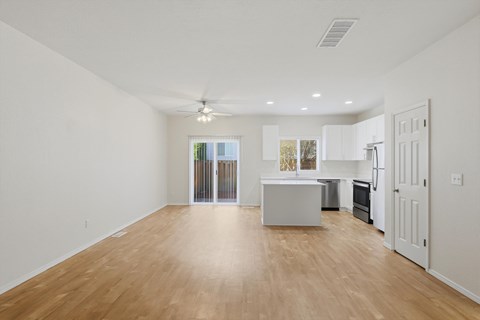 A spacious room with wooden flooring and a ceiling fan.