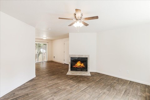A living room with a fireplace and a ceiling fan.