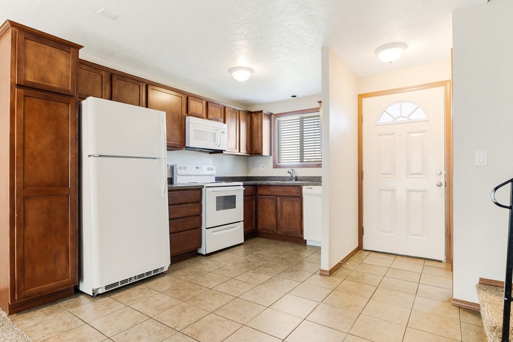 a kitchen with brown cabinets and white appliances