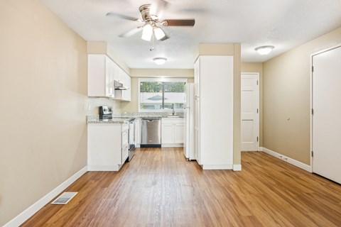 A kitchen with white cabinets and a wooden floor.