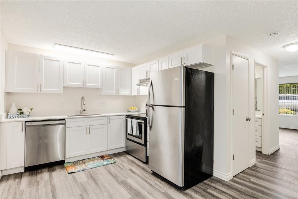 A kitchen with a black refrigerator and white cabinets.