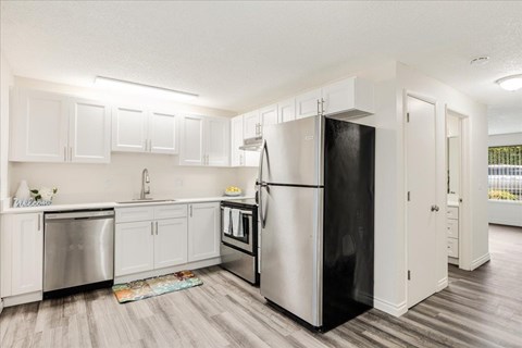 A kitchen with a black refrigerator and white cabinets.