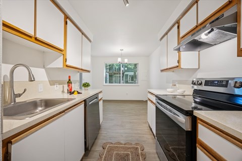 A modern kitchen with white cabinets and a black stove top oven.