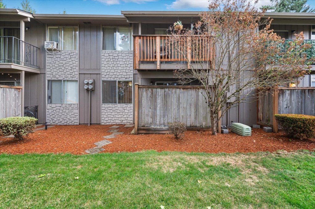 a Laurel Park Apartments Balcony with a fence and a tree in front of an apartment building