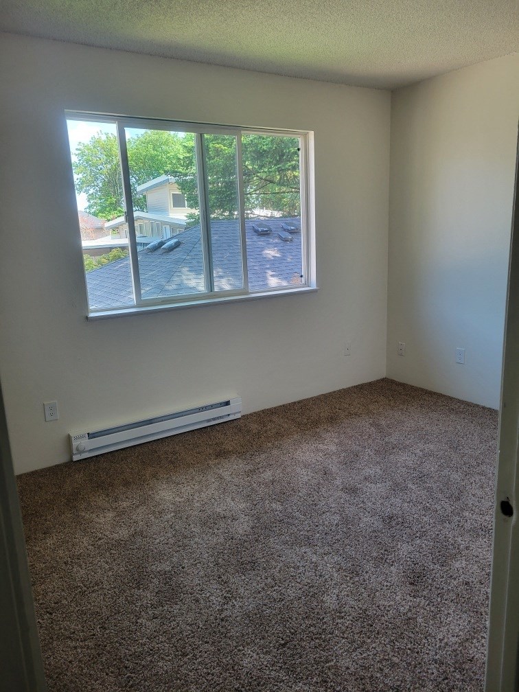 an empty room with a large window and carpet
