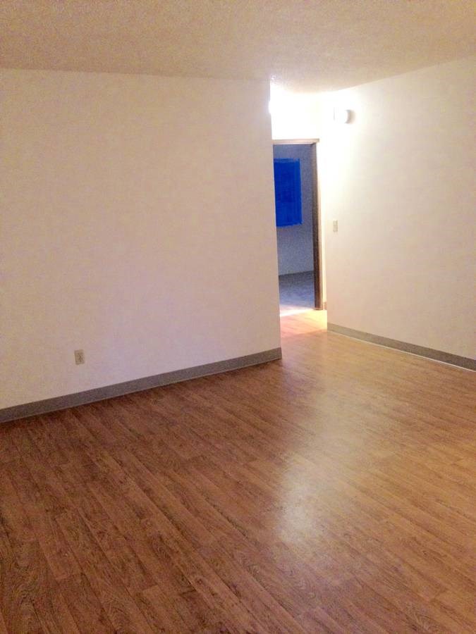an empty living room with white walls and wood floors