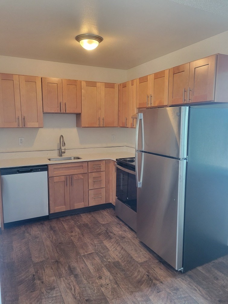 a kitchen with wooden cabinets and a stainless steel refrigerator