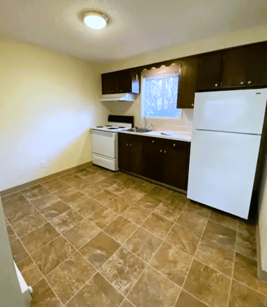 Nell Anna Court kitchen with a white refrigerator and brown tiled flooring.