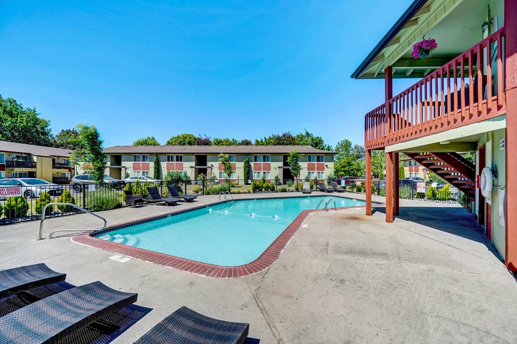 a swimming pool with lounge chairs and a building in the background