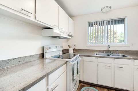 A kitchen with white cabinets and a granite countertop.