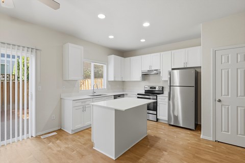 A kitchen with white cabinets and a wooden floor.