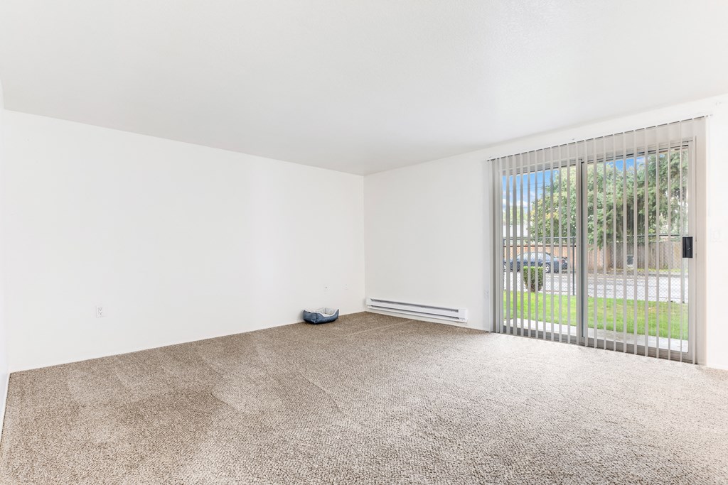 an empty living room with a large window and carpeting