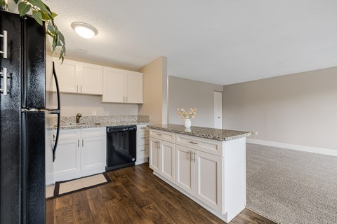 A kitchen with white cabinets and a black fridge.