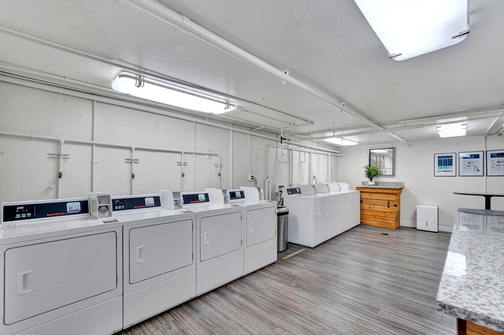 a laundry room with white washers and dryers and a counter with a sink Sunset Station Apartments Portland Oregon 