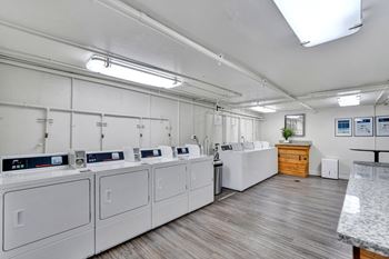 a laundry room with white washers and dryers and a counter with a sink