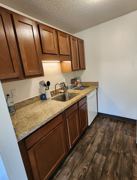 A kitchen with brown cabinets and a granite countertop.